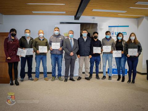 Un grupo de personas posando con certificados en un evento formal.