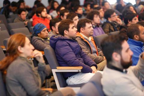 Un grupo de personas sentado en un auditorio prestando atención a una presentación.