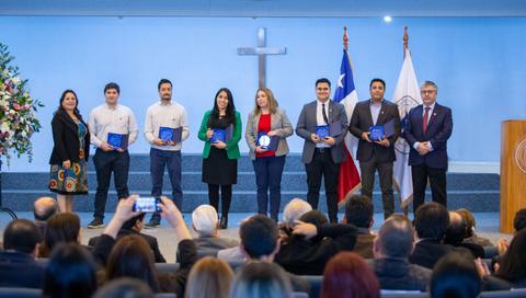 Ceremonia de entrega de certificados a varios profesionales en un acto formal.