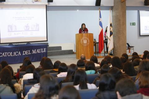 Una mujer habla en un podio frente a una audiencia en un evento en la universidad.