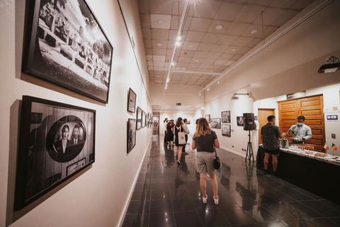 Una sala de exhibición con fotografías en las paredes y visitantes observando las obras.