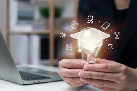 Una persona sostiene una bombilla que simboliza ideas educativas mientras hay íconos de logros académicos alrededor.