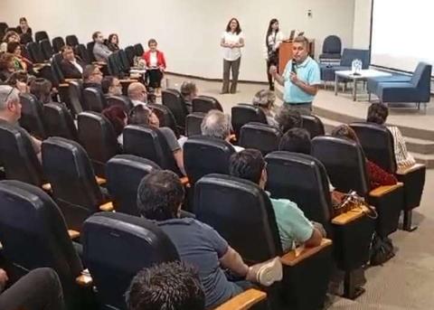 Un ponente habla frente a una audiencia en un salón de conferencias.