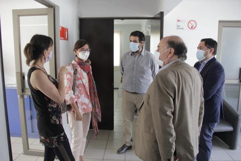 Un grupo de personas conversando en un entorno interior con mascarillas puestas.