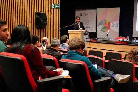 Un orador presenta en un evento ante un público atento en un auditorio.