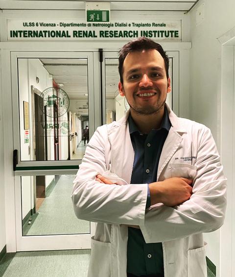 Un médico sonriente de pie en un pasillo de un instituto de investigación renal.