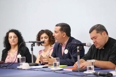 Un panel de discusión con cuatro personas sentadas frente a micrófonos en una mesa.
