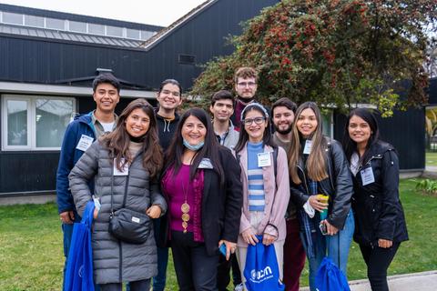 Un grupo de jóvenes posando sonrientes frente a un edificio moderno.