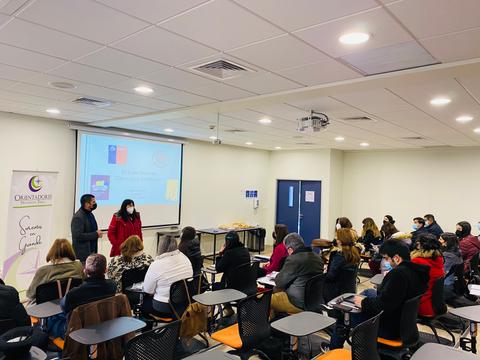 Una presentación en un aula con varias personas escuchando a dos ponentes.