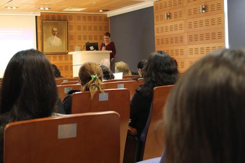 Una persona presenta en un auditorio mientras la audiencia observa.