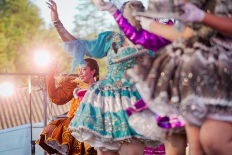 Un grupo de bailarines con trajes coloridos se presenta en un escenario iluminado.