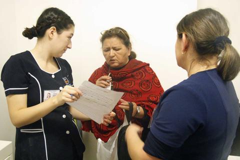 Un grupo de tres mujeres interactúa en un ambiente cerrado, donde una de ellas está revisando un documento.