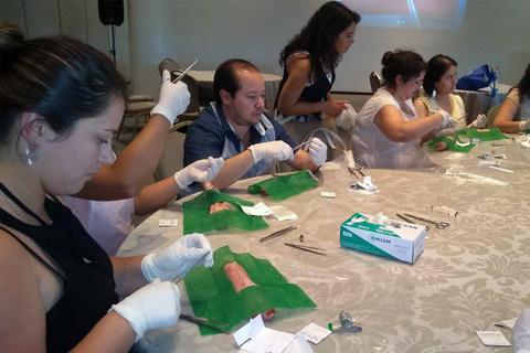 Un grupo de personas participa en un taller práctico sobre técnicas de cirugía o sutura en un ambiente colaborativo.