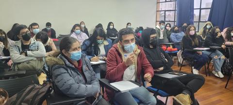 Un grupo de estudiantes en un aula durante una clase, usando mascarillas.