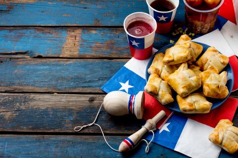 Una mesa decorada con banderas, snacks y bebidas típicas de una celebración.