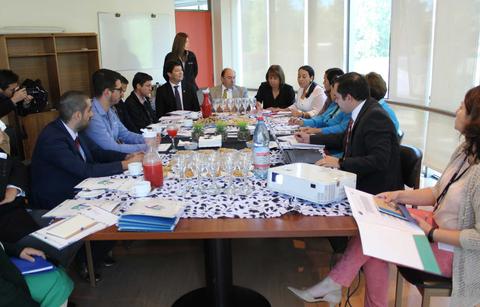 Un grupo de personas en una reunión alrededor de una mesa con documentos y bebidas.