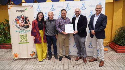 Un grupo de cinco personas posan para la foto sosteniendo un certificado en un evento formal.