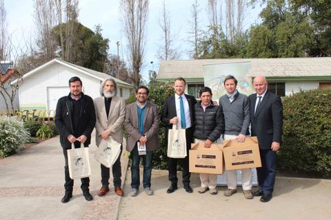 Un grupo de siete personas posan frente a una casa blanca en un entorno natural.