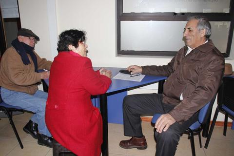 Tres personas conversan sentadas en una sala iluminada.