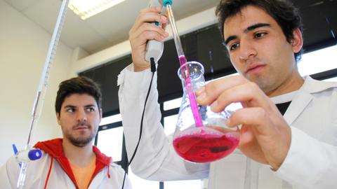Dos estudiantes realizan un experimento de química en un laboratorio.