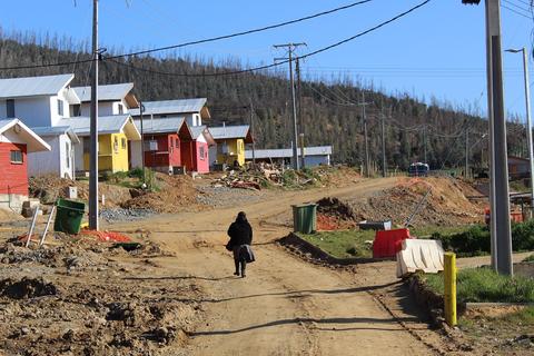 Una persona camina por un camino de tierra rodeado de casas de colores en una zona en construcción.