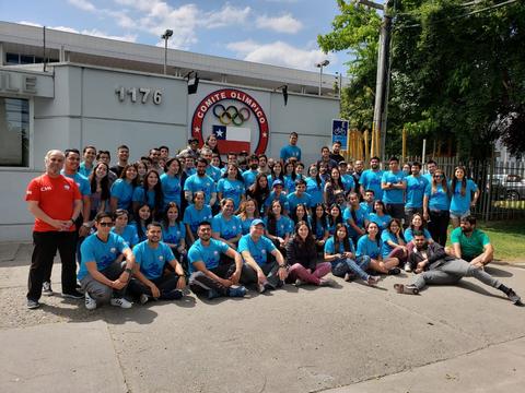 Grupo grande de personas posando frente al Comité Olímpico de Chile, luciendo camisetas azules.