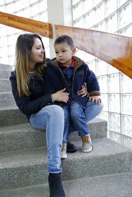 Una mujer sonríe mientras sostiene a un niño en una escalera.