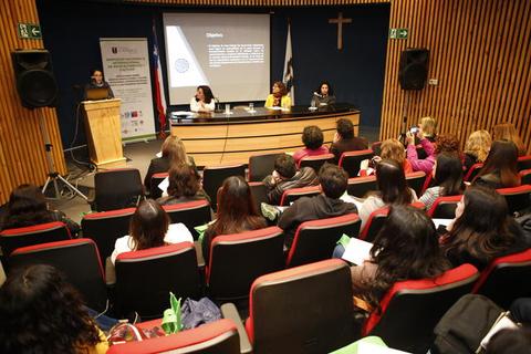 Una conferencia en un auditorio con un ponente en el escenario y varias personas en la audiencia.