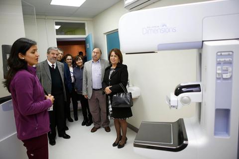 Un grupo de personas observa una máquina de mamografía durante una presentación en un centro médico.