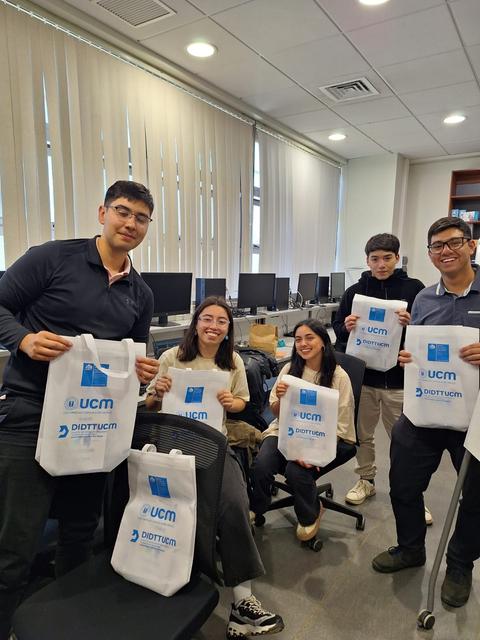 Un grupo de estudiantes posando con mochilas de la universidad UCM en una sala de clases.