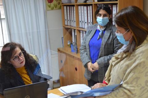 Tres personas conversan en una oficina mientras usan mascarillas.