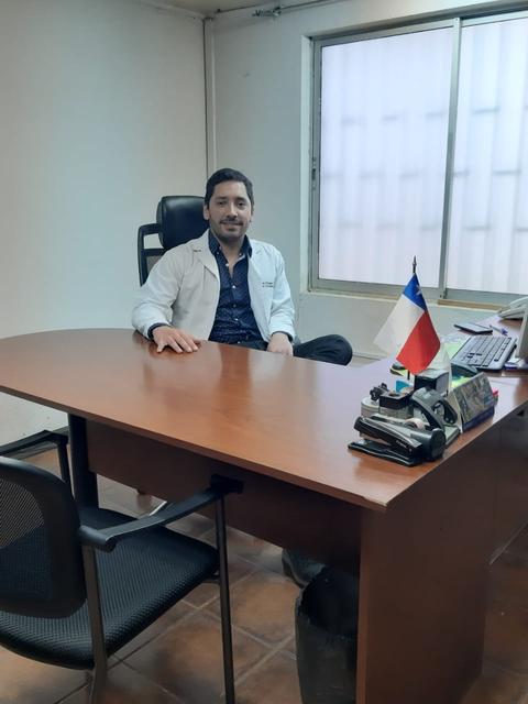 Un hombre vestido con una bata de médico se sienta en un escritorio en una oficina.