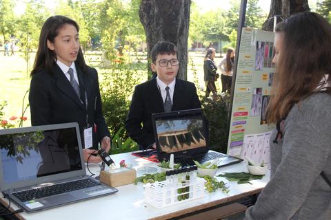 Estudiantes presentan un proyecto educativo en un evento al aire libre.