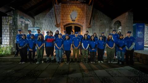 Un grupo de personas con camisetas azules posando en un lugar iluminado.