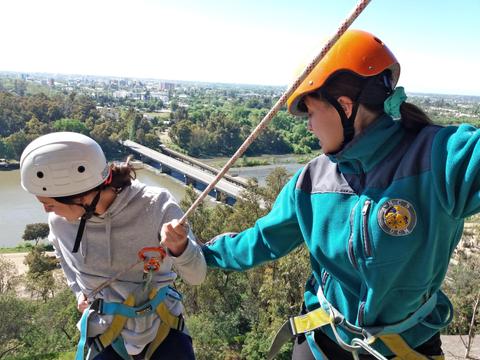 Dos personas realizan escalada en un entorno natural con vistas a la ciudad.
