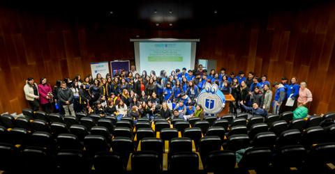 Un grupo grande de estudiantes y profesores posando en un auditorio tras un evento educativo.