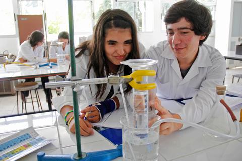 Dos estudiantes colaboran en un experimento de laboratorio con equipo de ciencia.