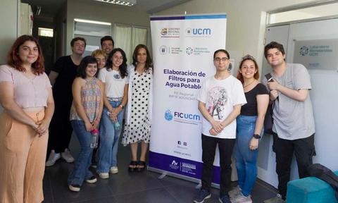 Grupo de personas posando frente a un cartel sobre la elaboración de filtros para agua potable.