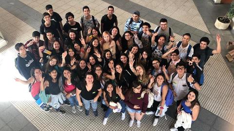 Un grupo grande de estudiantes está posando y sonriendo en un espacio abierto.