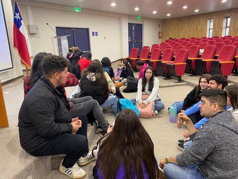 Un grupo de jóvenes sentados en círculo durante una actividad en un aula.