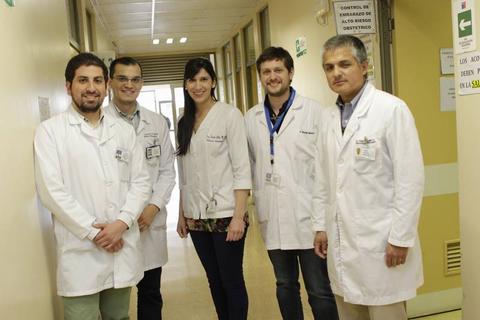 Grupo de cinco profesionales de la salud posando en un pasillo de un hospital.