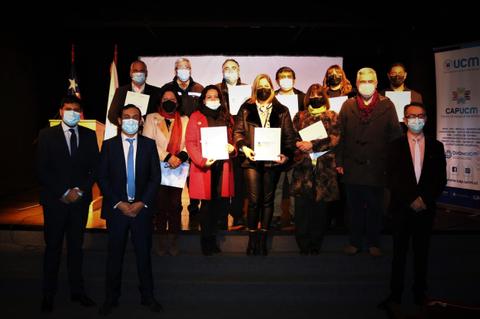 Grupo de personas posando en un evento, sosteniendo certificados y usando mascarillas.