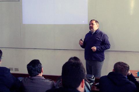 Un hombre está dando una charla frente a una audiencia en un aula.