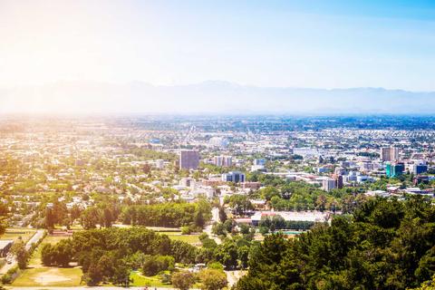 Una vista panorámica de una ciudad con vegetación y montañas al fondo.