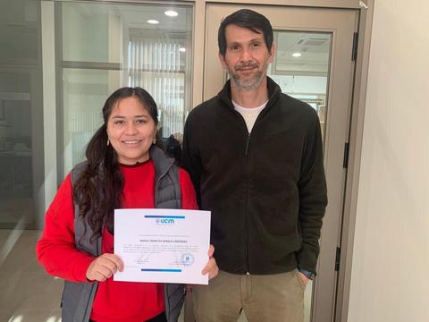 Una mujer y un hombre posan juntos sosteniendo un certificado en un entorno de oficina.