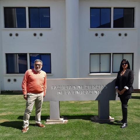 Dos personas posan frente a un edificio de la Facultad de Ciencias de la Educación.