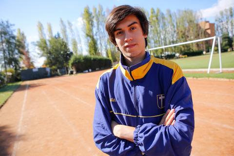 Un joven deportista posa con calma en una pista de atletismo.