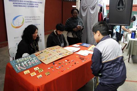 Una feria donde se exhiben artesanías y manualidades mientras un niño observa los productos en un stand.