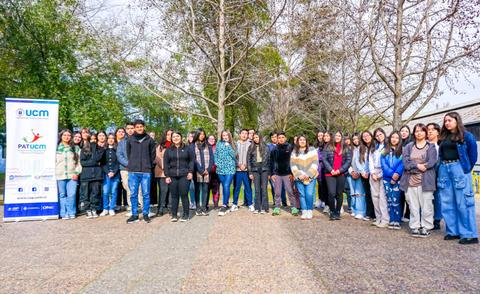 Un grupo de estudiantes posando junto a un cartel en un entorno natural.