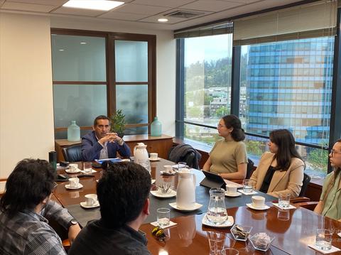 Una reunión de trabajo en una sala con varias personas sentadas alrededor de una mesa.